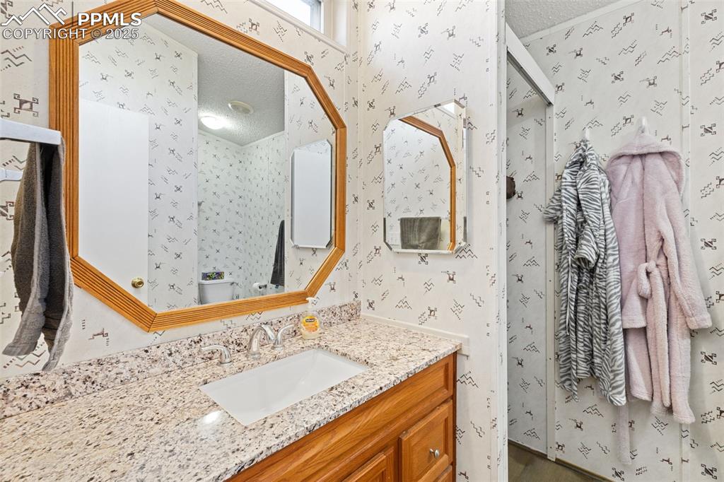 20480 Drennan Road Colorado Springs, CO 80928 - Photo 30 of 47 a bathroom with a granite countertop sink a mirror and shower