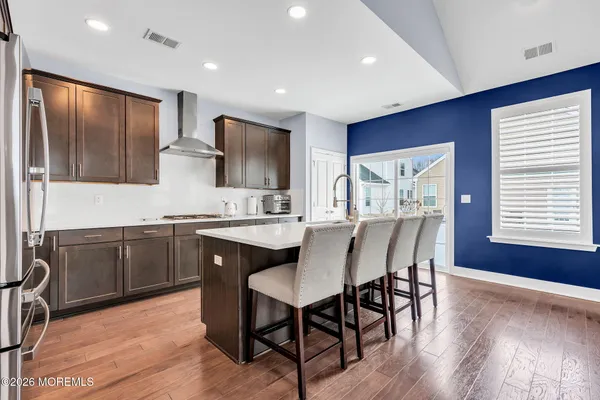 a kitchen with stainless steel appliances granite countertop wooden cabinets a refrigerator a sink a stove a dining table and chairs