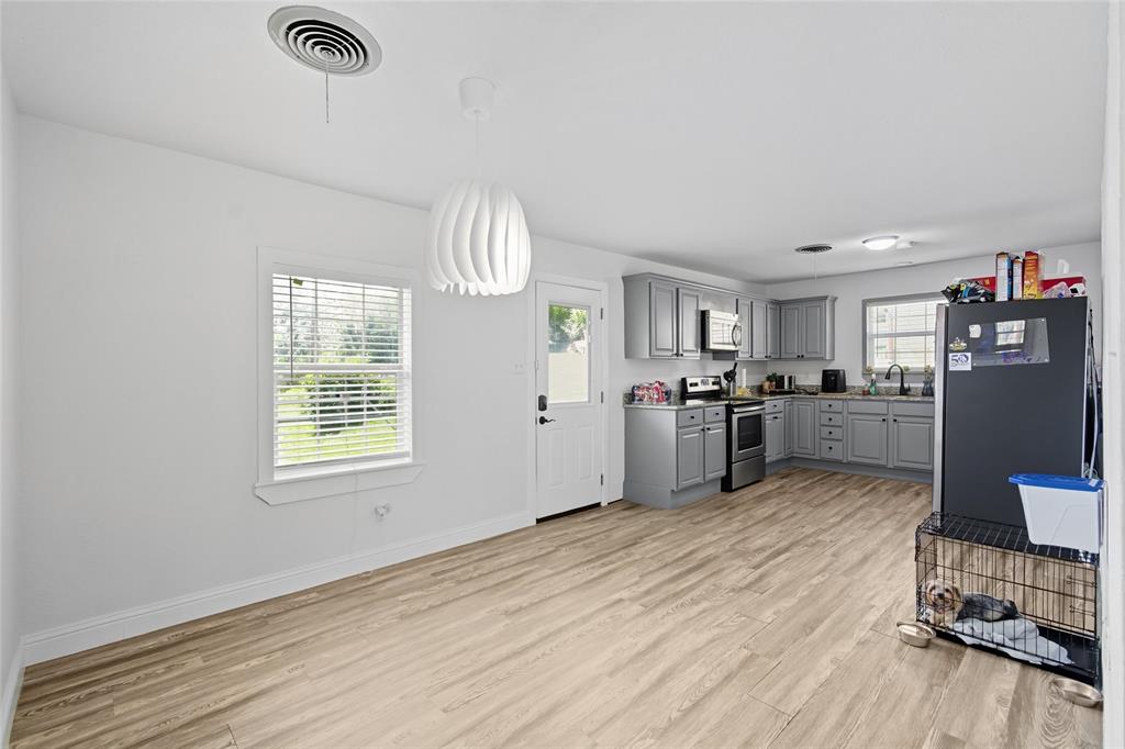 421 East Tarrant Road Grand Prairie, TX 75050 - Photo 16 of 32 Kitchen with gray cabinets, appliances with stainless steel finishes, hanging light fixtures, and light wood-type flooring
