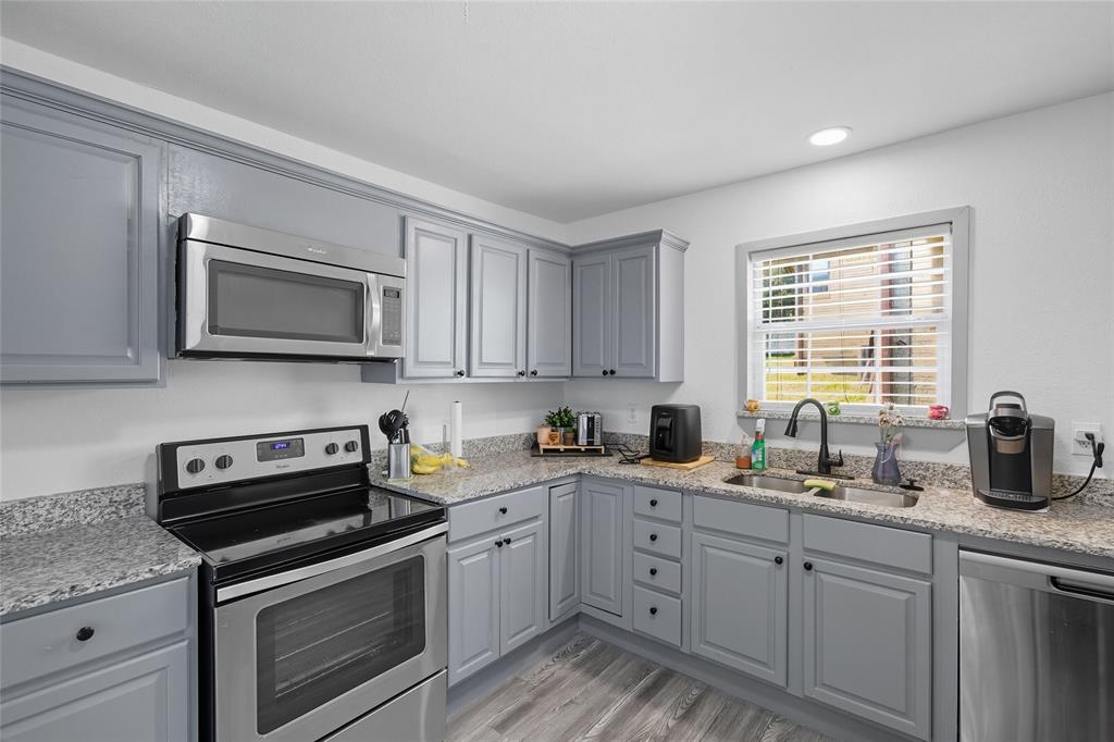 421 East Tarrant Road Grand Prairie, TX 75050 - Photo 19 of 32 Kitchen with appliances with stainless steel finishes, gray cabinets, light stone countertops, light wood-style flooring, and recessed lighting