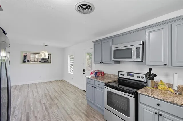 a kitchen with stainless steel appliances granite countertop a stove a sink and a microwave
