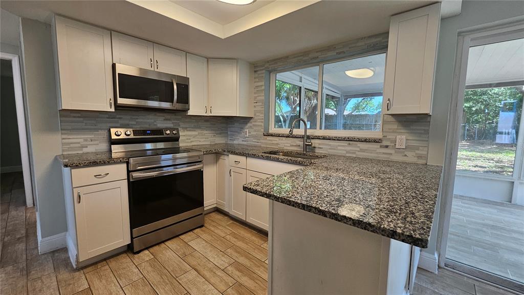 6412 Pawling Avenue Port Richey, FL 34668 - Photo 8 of 24 a kitchen with stainless steel appliances granite countertop a sink stove and microwave