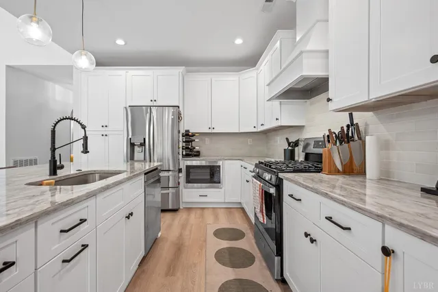 a kitchen with stainless steel appliances granite countertop a sink a stove a refrigerator and cabinets