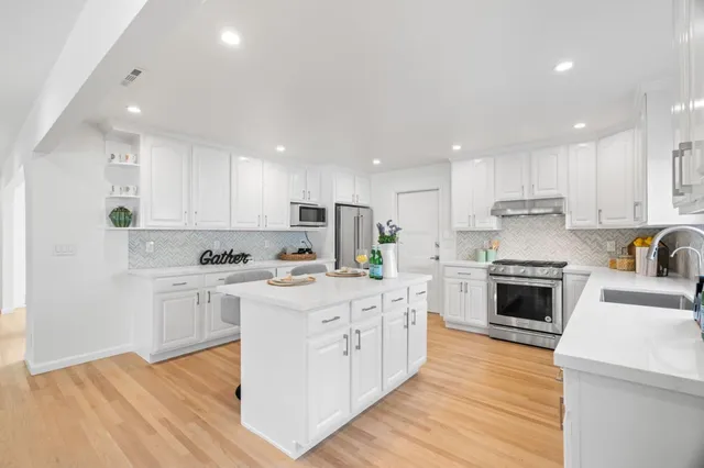 a large kitchen with cabinets wooden floor and stainless steel appliances