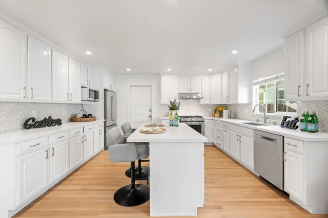 a kitchen with white cabinets a sink dishwasher and white appliances