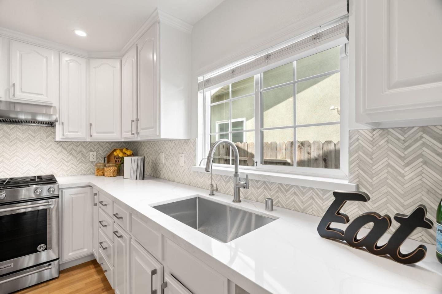1002 Oaktree Drive San Jose, CA 95129 - Photo 19 of 45 a kitchen with stainless steel appliances a sink a stove and a white counter tops with wooden floors