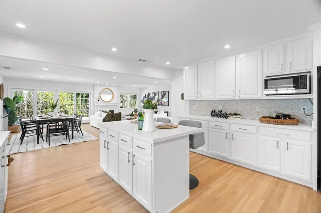 a kitchen with stainless steel appliances granite countertop a stove top oven a sink dishwasher and white cabinets with wooden floor