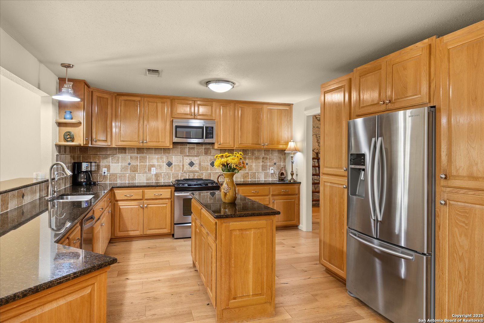 127 Camp Alzafar Road Boerne, TX 78006 - Photo 14 of 50 a kitchen with granite countertop a refrigerator oven a sink dishwasher and cabinets with wooden floor