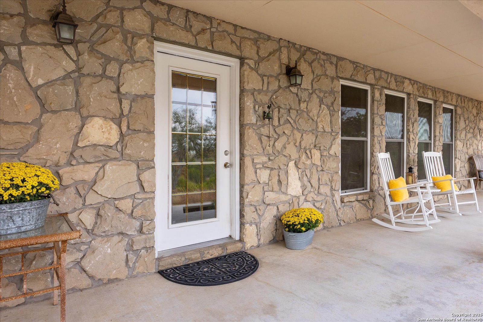127 Camp Alzafar Road Boerne, TX 78006 - Photo 4 of 50 a view of a door with table and chairs and potted plants
