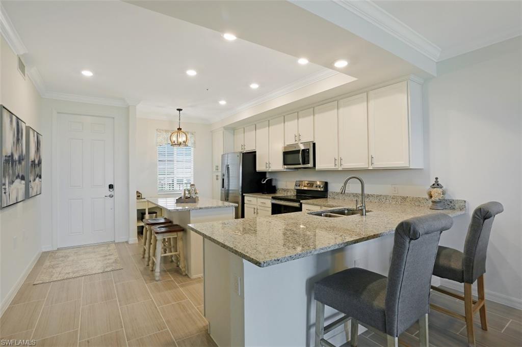 43010 Greenway Boulevard, Unit 234 Punta Gorda, FL 33982 - Photo 6 of 22 a kitchen with stainless steel appliances granite countertop a table chairs sink refrigerator and cabinets