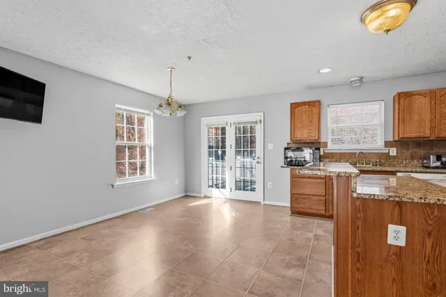 a large kitchen with kitchen island granite countertop a stove a sink a window and dining table