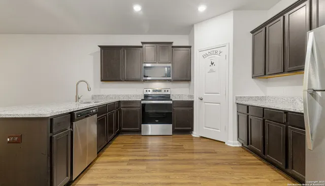 a kitchen with granite countertop a refrigerator stove top oven and wooden floor