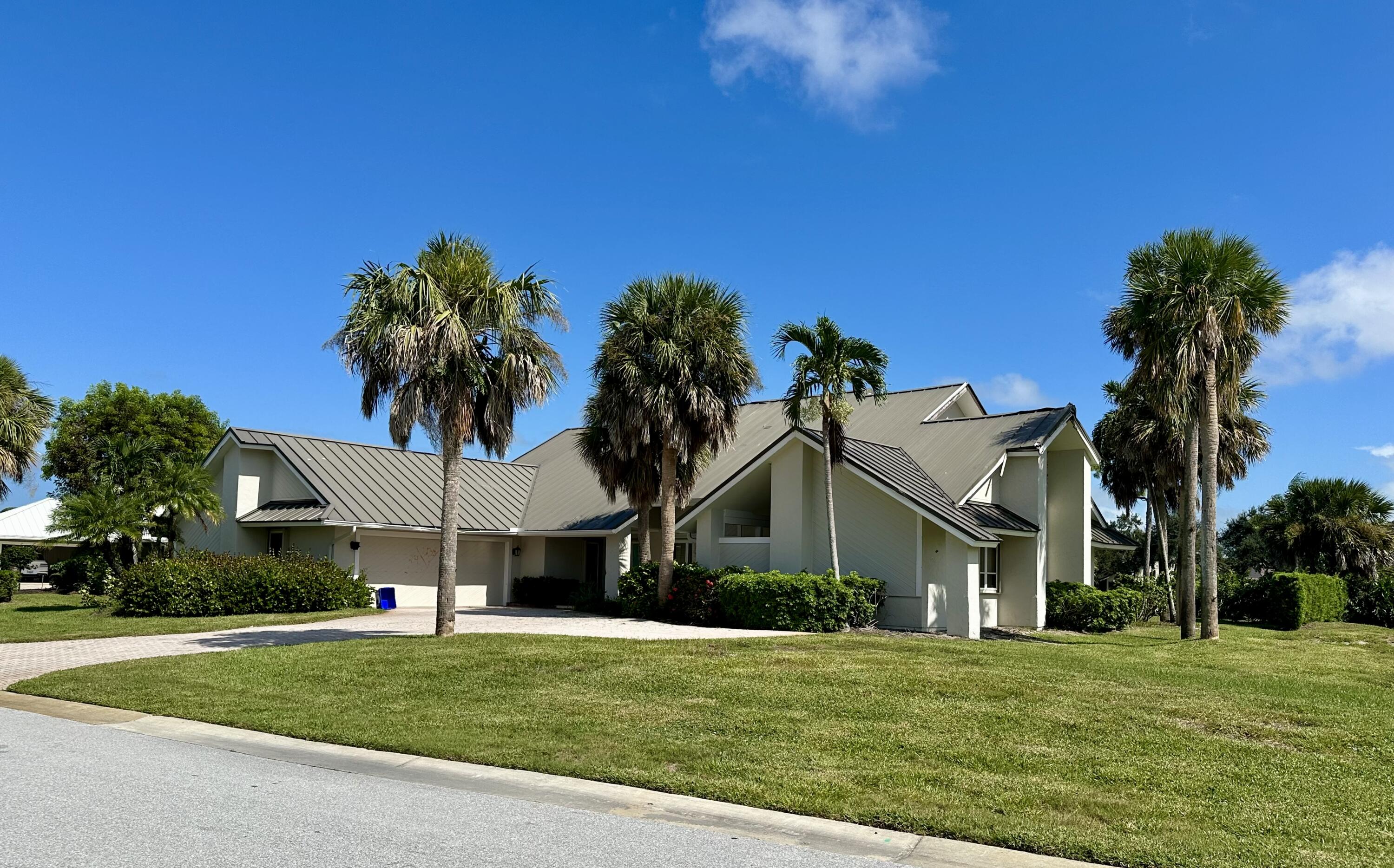 a front view of a house with a yard and palm trees