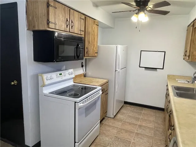 a living room with stainless steel appliances kitchen island granite countertop a sink and a refrigerator