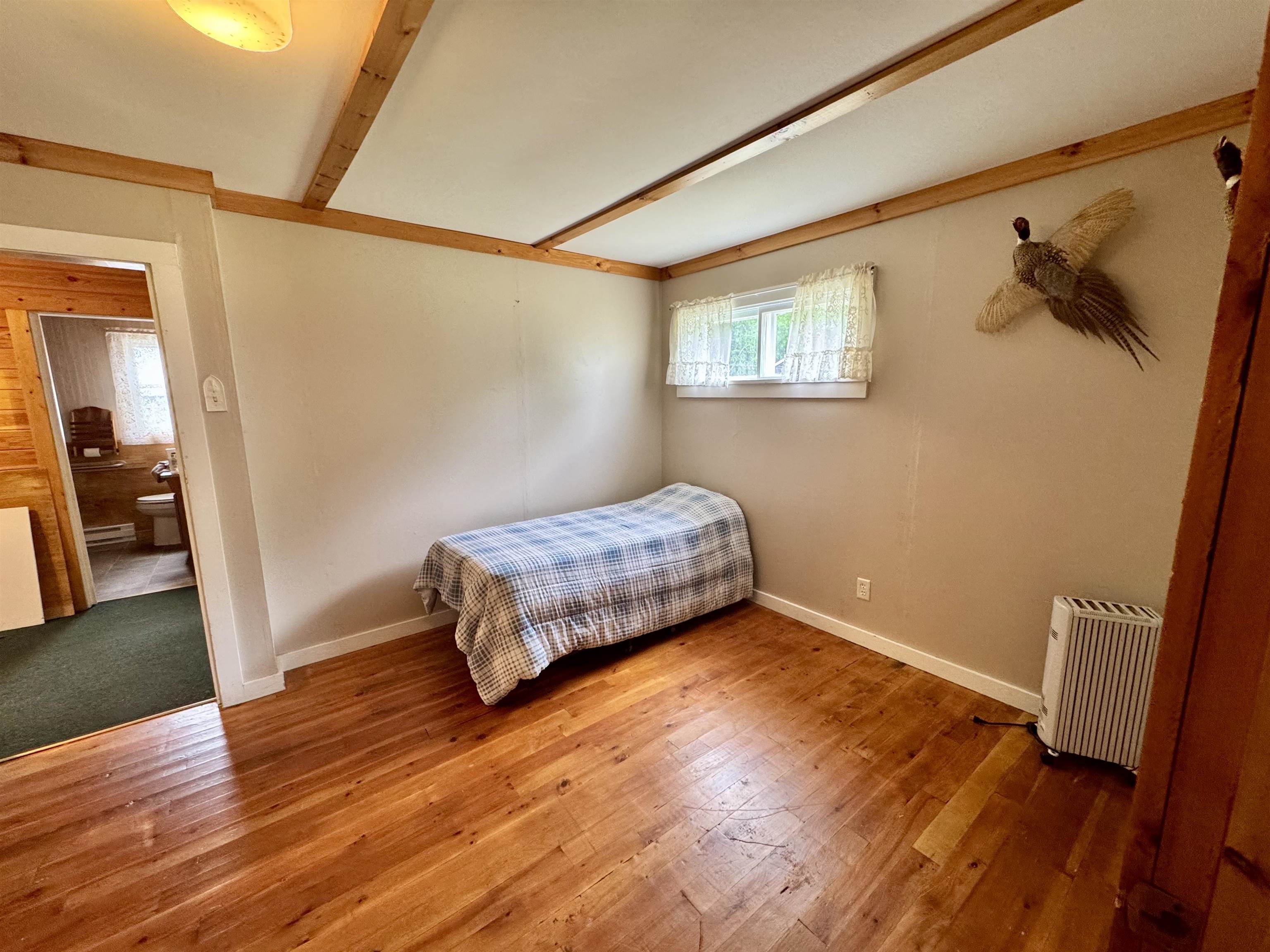 9724 State Highway 1 Isabella, MN 55607 - Photo 12 of 21 Bedroom featuring baseboard heating, beam ceiling, wood finished floors, and baseboards