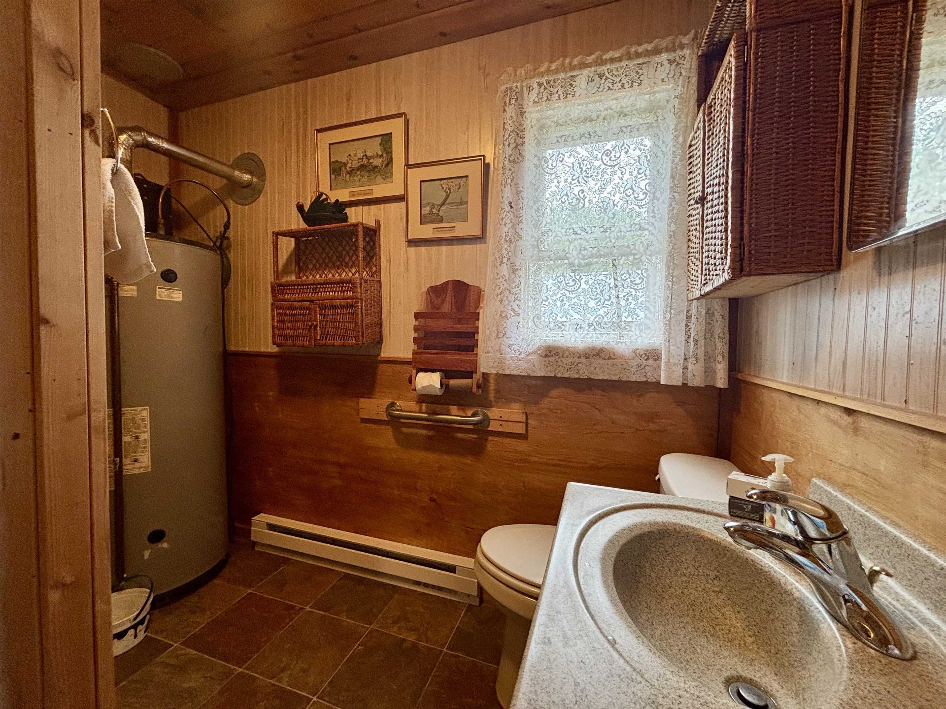 9724 State Highway 1 Isabella, MN 55607 - Photo 15 of 21 Bathroom featuring a baseboard heating unit, gas water heater, toilet, healthy amount of natural light, and wooden walls