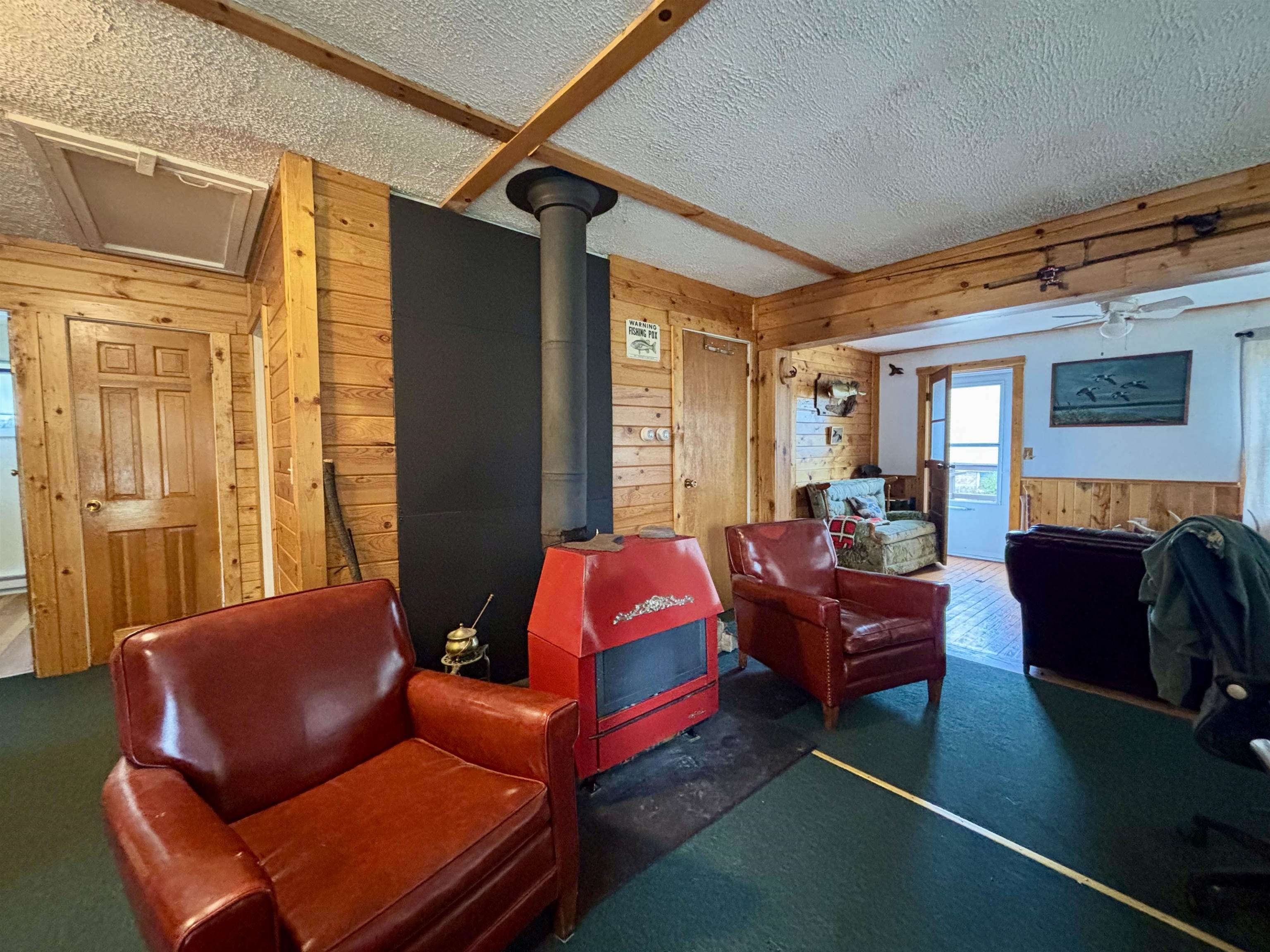 9724 State Highway 1 Isabella, MN 55607 - Photo 10 of 21 Living area with wood walls, a textured ceiling, and a wood stove