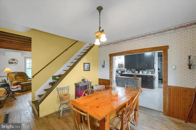 a dining room with wooden floor a chandelier a wooden table and chairs