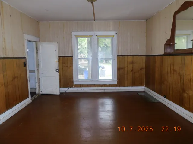 a view of an empty room with a window and wooden floor