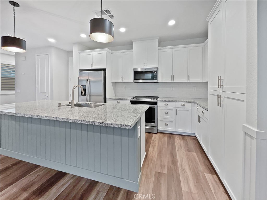 38352 Windingwalk Drive Murrieta, CA 92563 - Photo 15 of 28 a kitchen with kitchen island granite countertop wooden floors and white cabinets