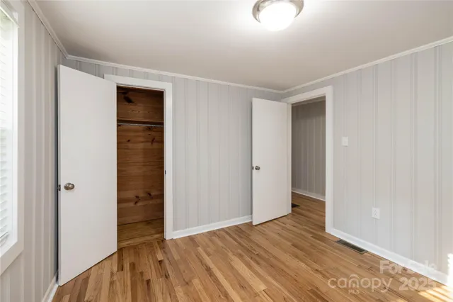 a view of an empty room with closet and wooden floor