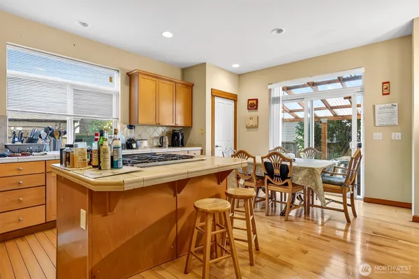 a kitchen with stainless steel appliances granite countertop dining table chairs and a large window