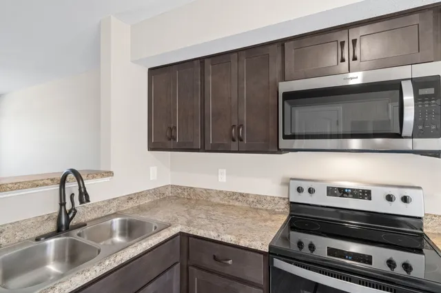 an empty room with wooden floor cabinet and windows
