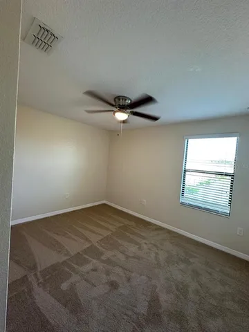 an empty room with windows and chandelier fan