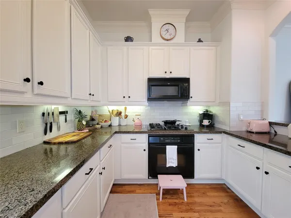 a kitchen with granite countertop a sink a stove and cabinets