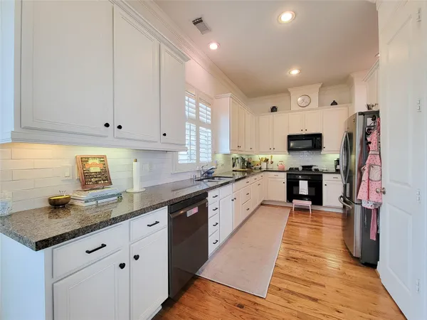 a kitchen with granite countertop a sink a counter top space stainless steel appliances and cabinets