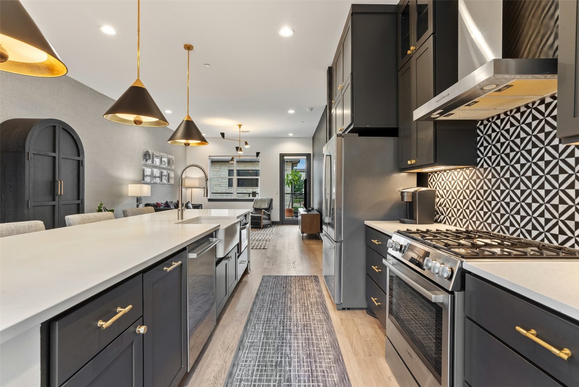 4507 Unity Circle Austin, TX 78731 - Photo 36 of 37 Kitchen featuring appliances with stainless steel finishes, wall chimney exhaust hood, light wood-style floors, decorative light fixtures, and open floor plan