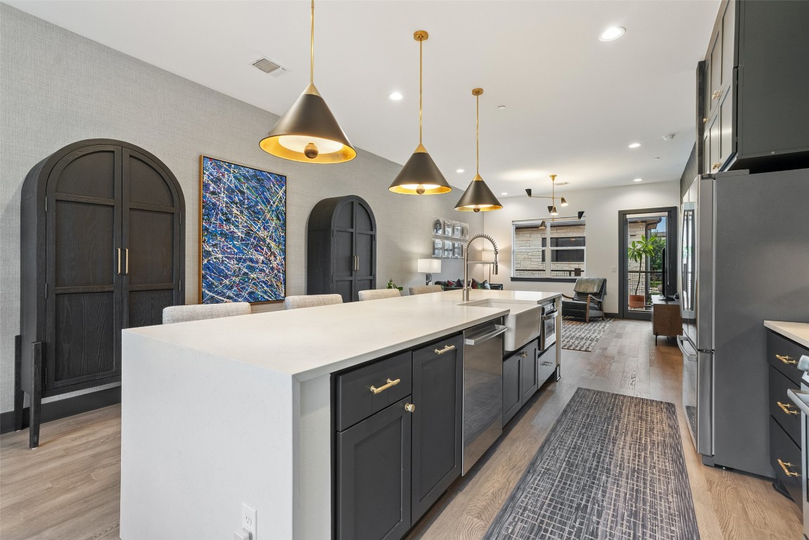 4507 Unity Circle Austin, TX 78731 - Photo 37 of 37 Kitchen featuring light wood-style floors, stainless steel appliances, dark cabinets, hanging light fixtures, and open floor plan