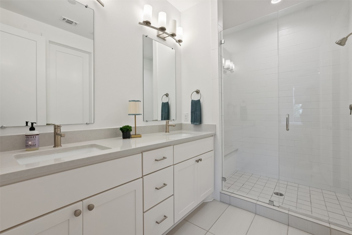 4507 Unity Circle Austin, TX 78731 - Photo 23 of 37 Bathroom featuring a shower stall, double vanity, and light tile patterned floors