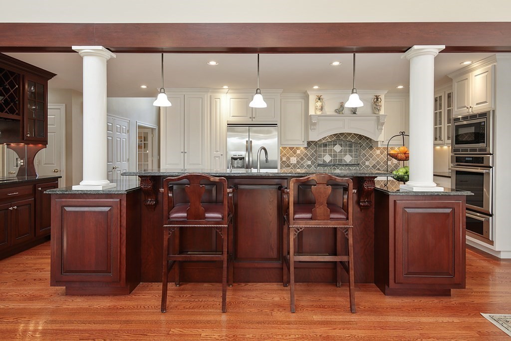 31 Draper Road Dover, MA 02030 - Photo 15 of 41 a kitchen with stainless steel appliances kitchen island granite countertop a table chairs and a refrigerator