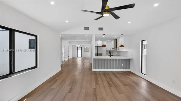 a large kitchen with stainless steel appliances a large counter top a sink a refrigerator and a window