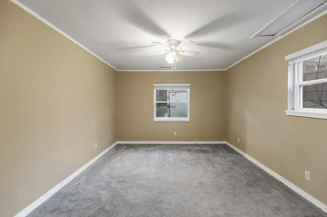 an empty room with windows and fan