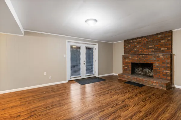 an empty room with wooden floor fireplace and windows