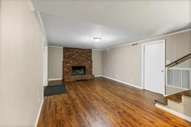 a view of empty room with wooden floor and fireplace