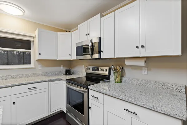a kitchen with granite countertop white cabinets stainless steel appliances and a sink