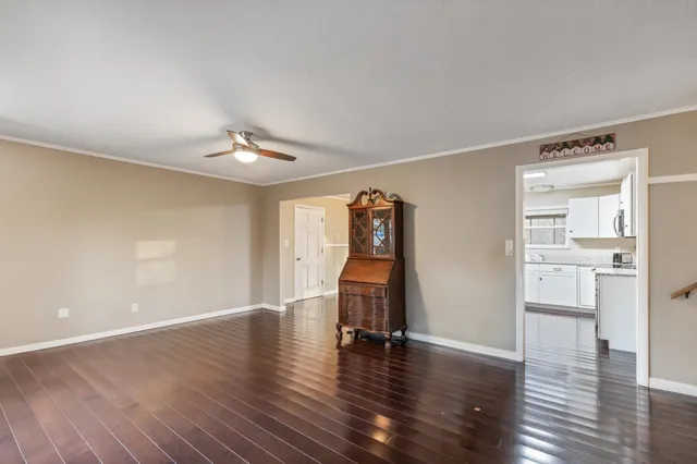 a view of an empty room with wooden floor and a window
