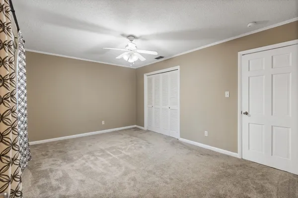 an empty room with a chandelier fan and windows