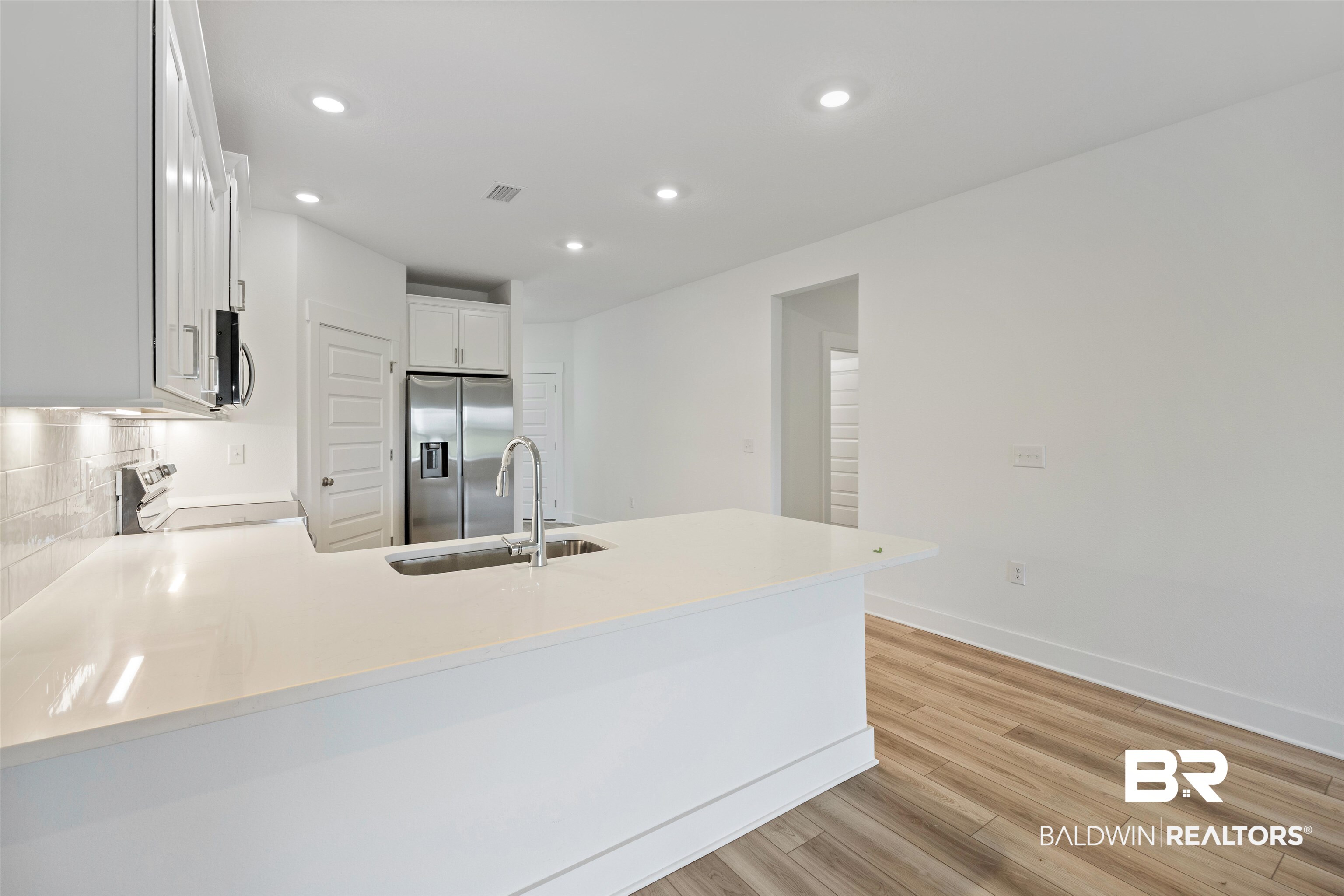 9986 Weller Cove Foley, AL 36535 - Photo 14 of 43 Kitchen featuring a peninsula, white cabinets, appliances with stainless steel finishes, light wood-type flooring, and recessed lighting
