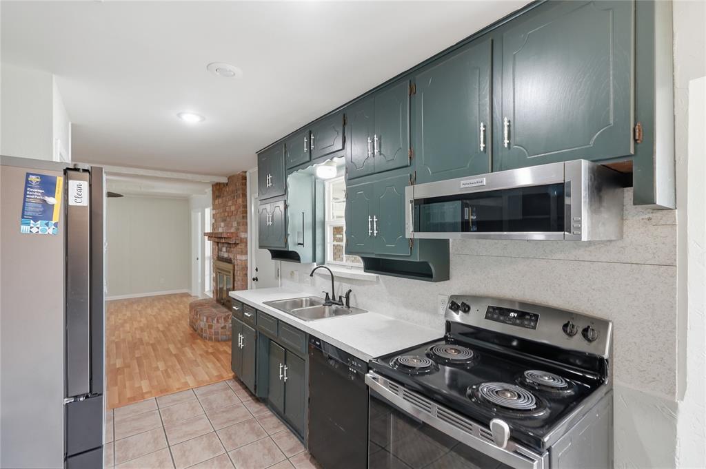 837 Springdale Road Bedford, TX 76021 - Photo 11 of 28 Kitchen featuring dark teal cabinetry, stainless steel appliances including a refrigerator, range, and built-in microwave, white countertops, and a double basin sink with a gooseneck faucet