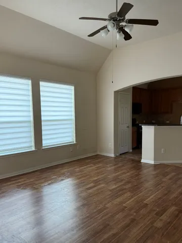 a view of an empty room with a window and wooden floor