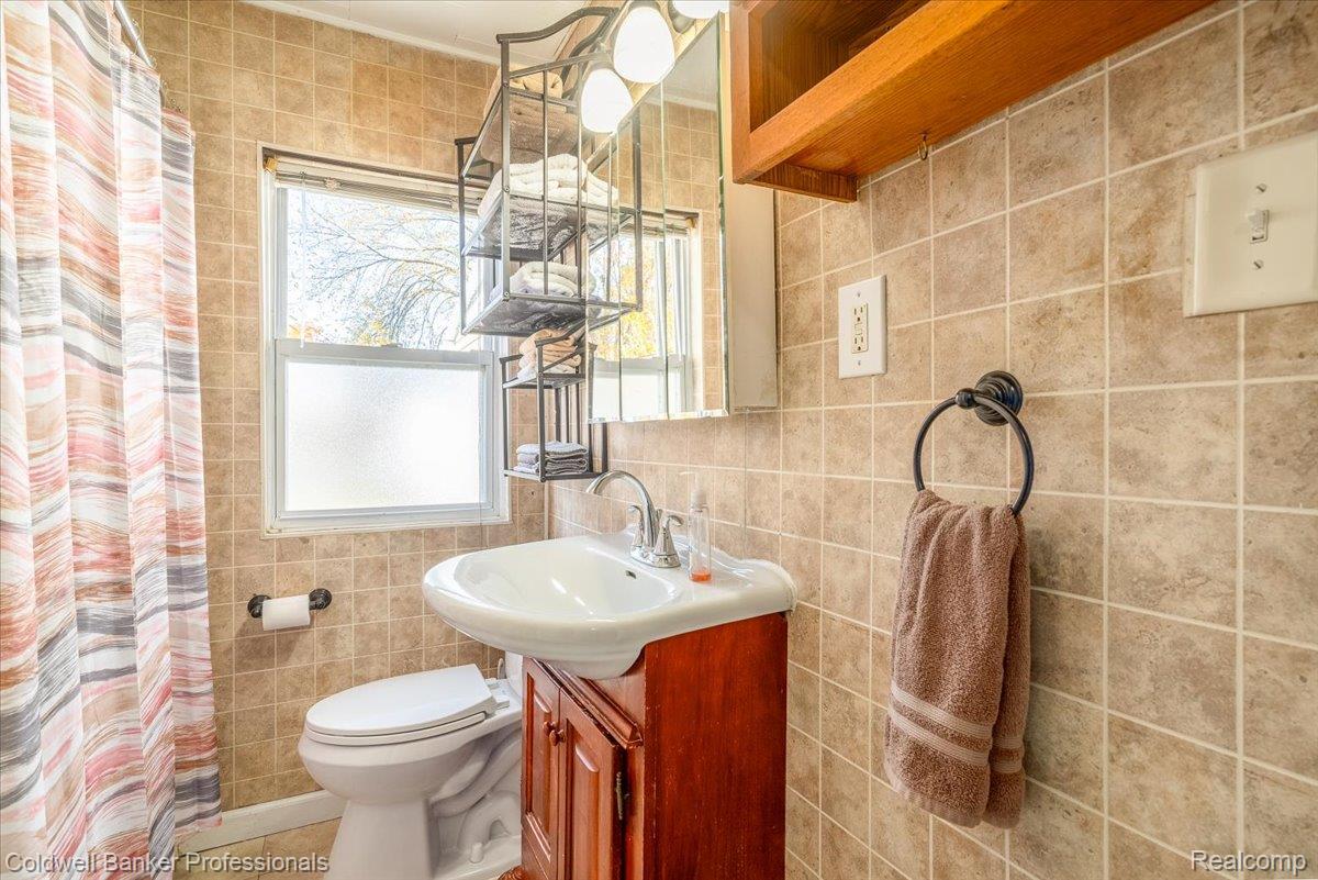 3582 Swanson Street Wayne, MI 48184 - Photo 19 of 30 Full bathroom with tile walls, vanity, a shower with shower curtain, and tile patterned floors