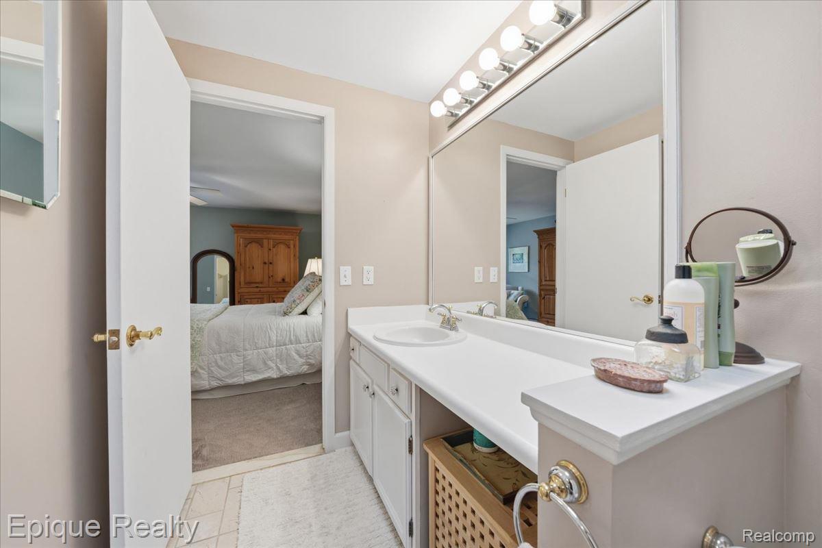 26 Kirks Court Rochester, MI 48309 - Photo 24 of 44 Bathroom vanity featuring an integrated sink, expansive mirror with overhead lighting, and ample cabinet storage