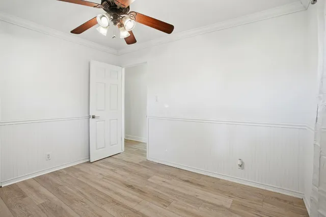 an empty room with wooden floor fan and windows