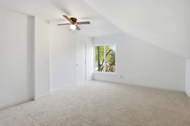 an empty room that has a window with a fan