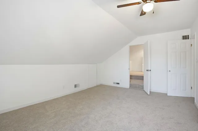 an empty room with a ceiling fan and carpet