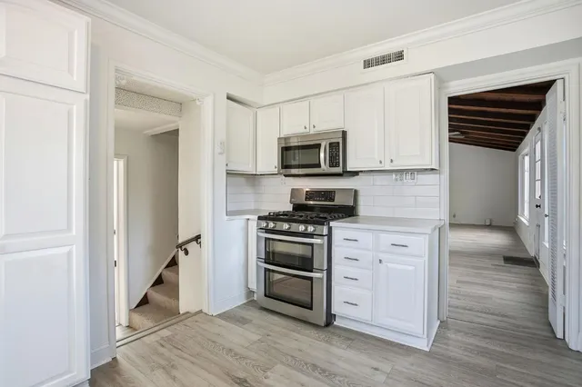 a kitchen with cabinets stainless steel appliances and wooden floor